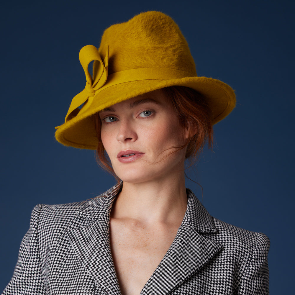 Woman wearing a mustard felt trilby with bow