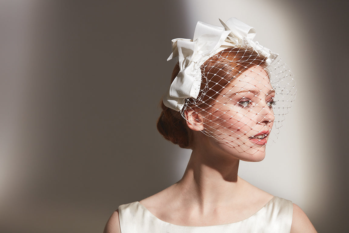 Young woman in a wedding dress wearing a silk bow headband with veil