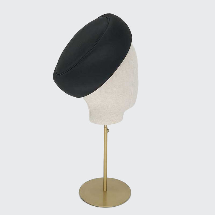 Photo of a black silk Jackie O pillbox on a linen display head