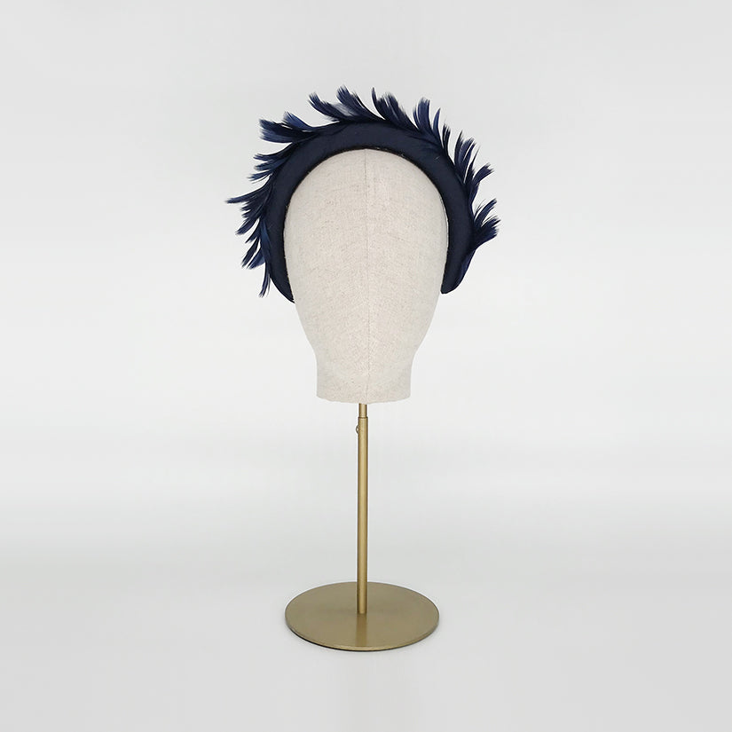 Photo of a navy goose feather headband on a linen display head