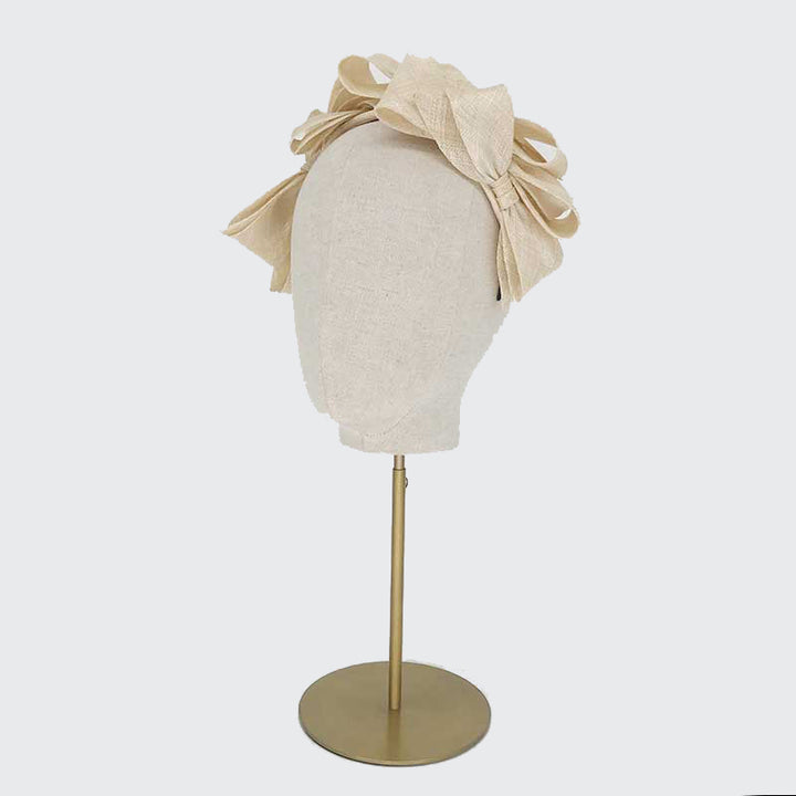 Side view of a natural fine straw bow headband on a linen display head
