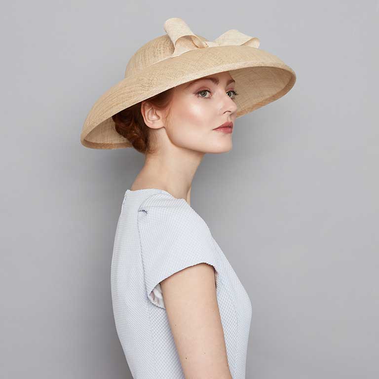 Woman with red hair wearing a pale blue dress and a natural fine straw Dior bell with a bow