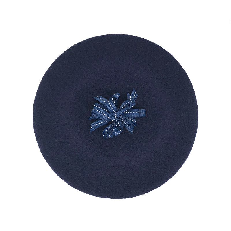 Photo of a navy wool beret with a navy ribbon pom
