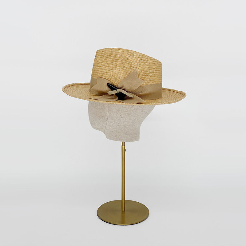 Side view of a natural panama trilby with a grosgrain bow on a linen display head