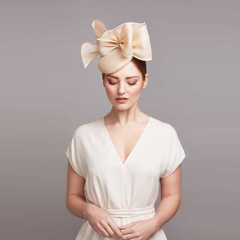 Woman with red hair wearing a white dress and a natural pillbox with bows