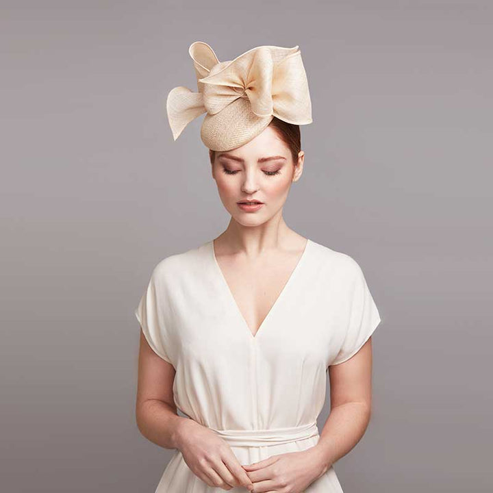 Woman with red hair wearing a white dress and a natural pillbox with bows