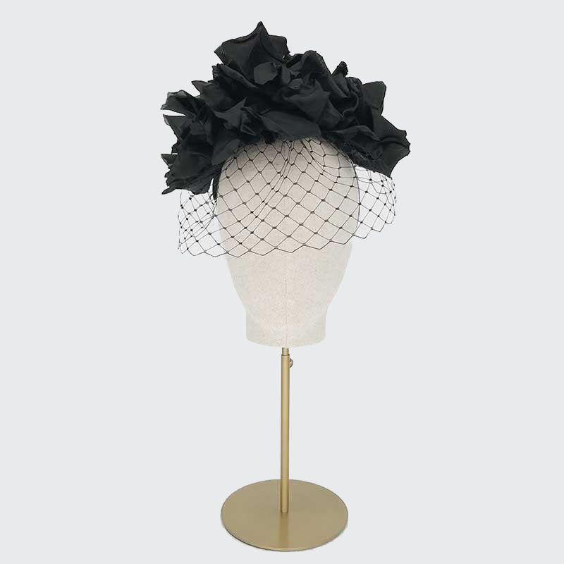 Photo of a black silk flower headdress and face veil on a linen display head