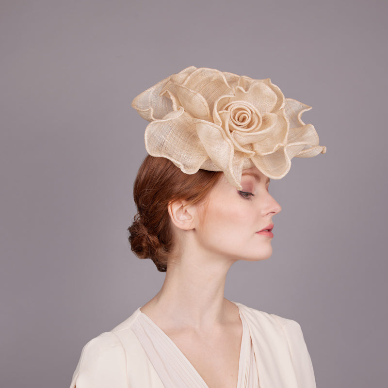 Woman with red hair wearing a white top and a natural rolled rose pillbox