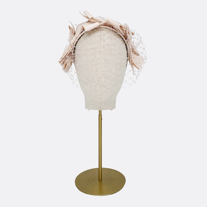 Photo of a pale pink silk bow headband with face veil on a linen display head