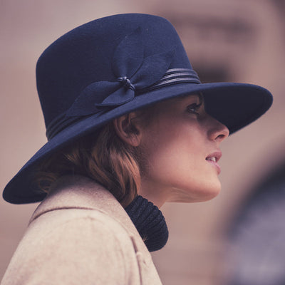 Girl wearing a navy fedora with leather band 