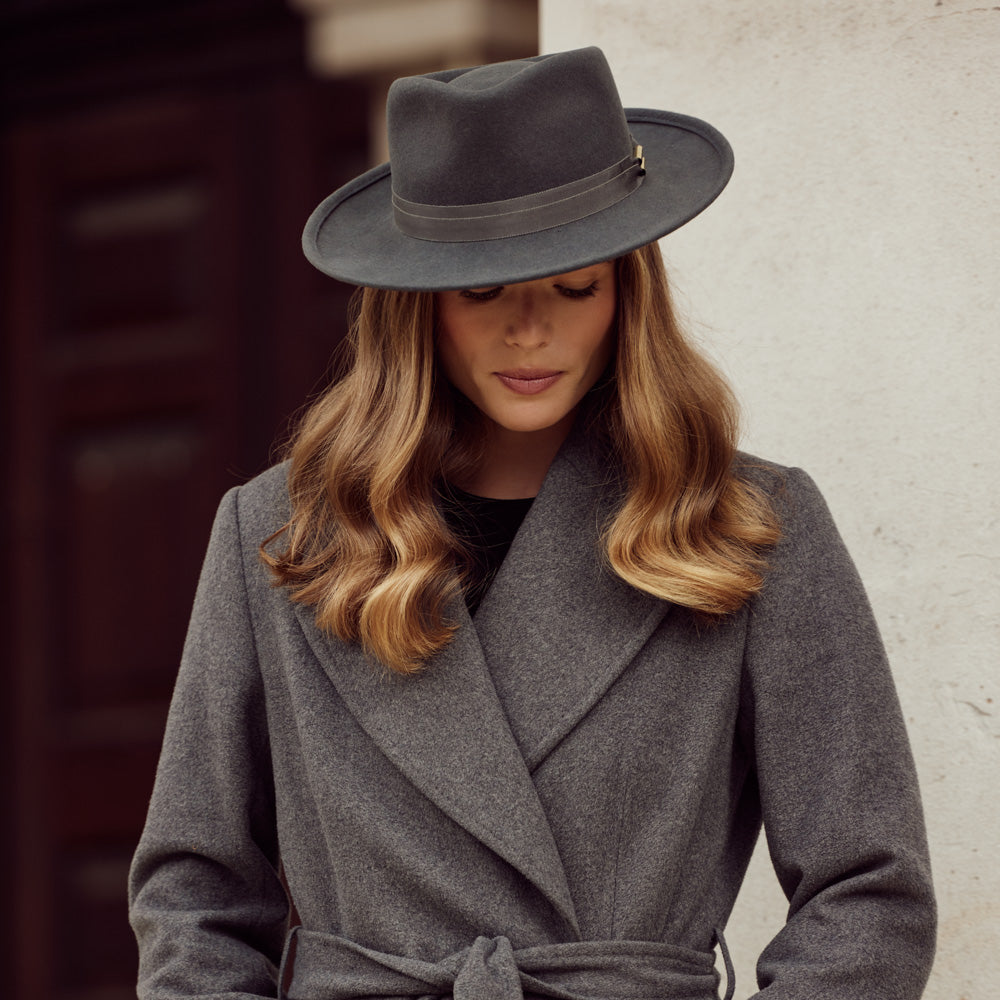 Woman wearing a grain coat and a grey wool fedora with a copper detail