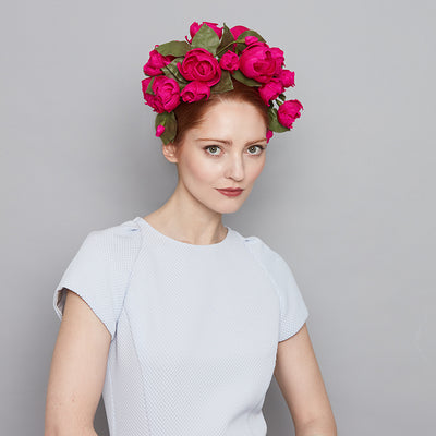 Woman with red hair wearing a pale blue dress and a hot pink silk roses headdress