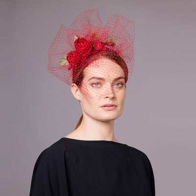 Woman with red hair wearing a black dress with red silk roses crescent headband with veiling