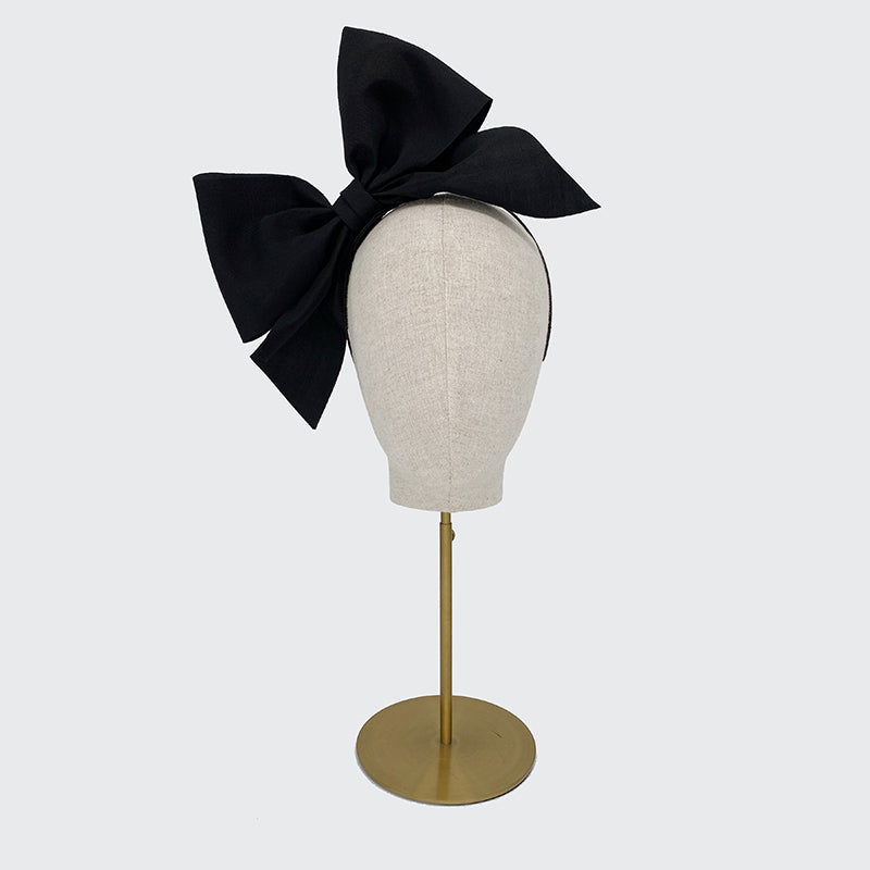 Black grosgrain bow headband on a linen display head