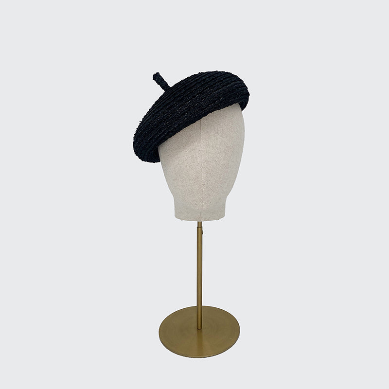 Photo of a black vintage straw beret on a linen display head