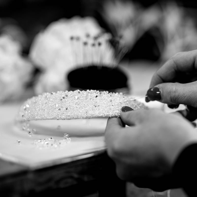 Two hands hand-beading a bridal headpiece