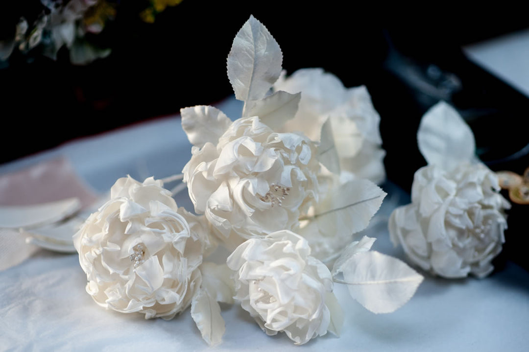 Ivory silk roses with white leaves on a table
