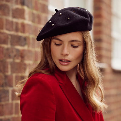 Woman with long hair wearing a red velvet jacket and a black stud beret