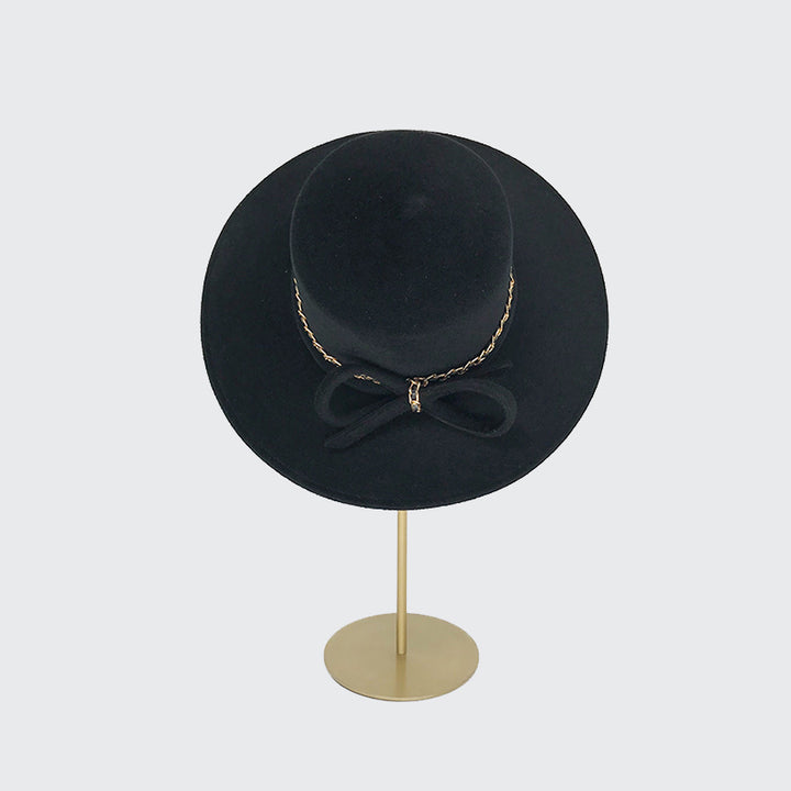 Black view of a black velour felt with gold chain detail on a linen display head