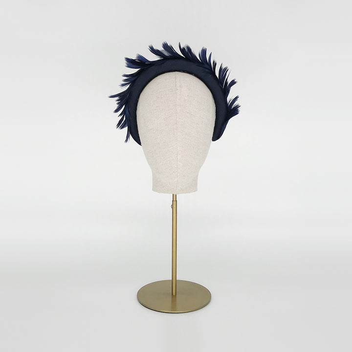 Photo of a navy goose feather headband on a linen display head