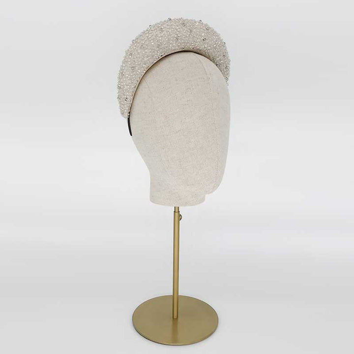 Side view of a silver grey silk beaded raised headband on a linen display head