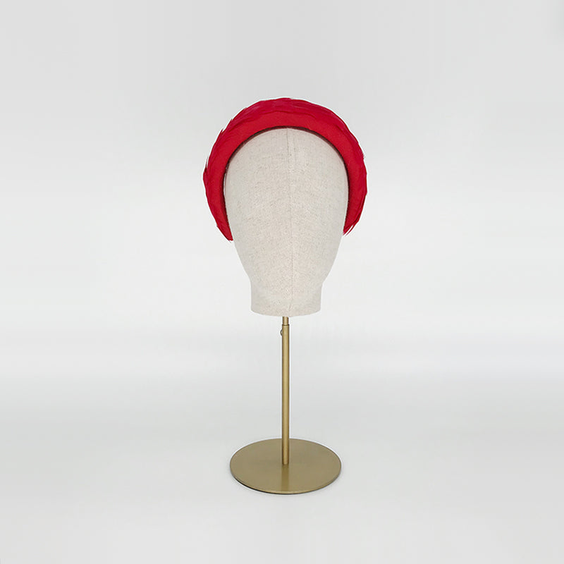 Photo of a red goose feather headband on a linen display head