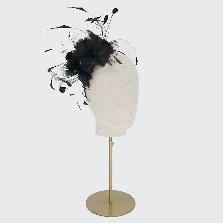 Side view of a black feather flower headband on a linen display head