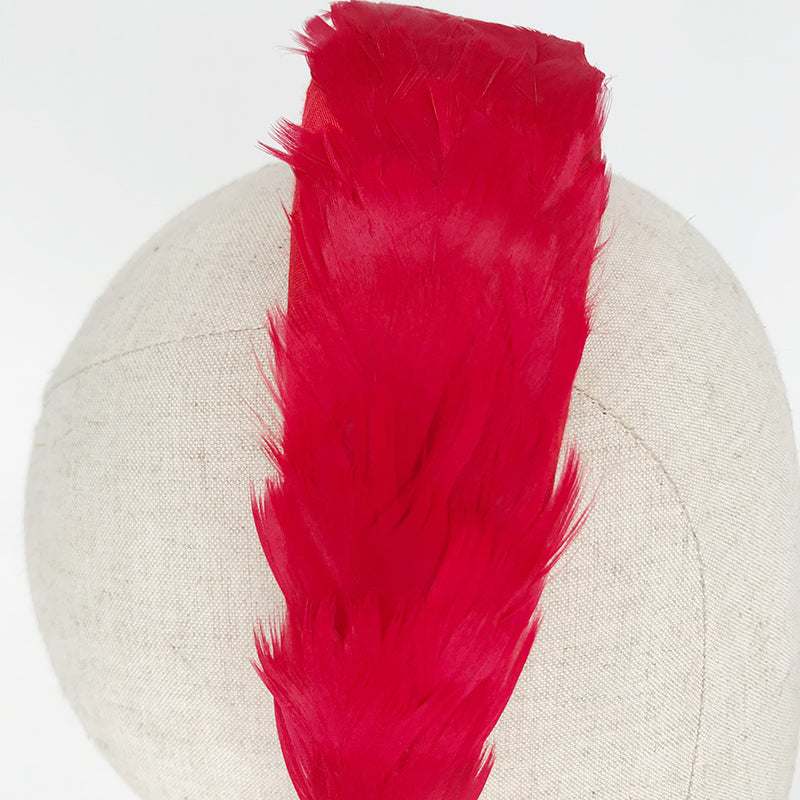 Close up of a red goose feather headband on a linen display head
