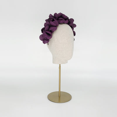 Side view of a purple grazia petal headdress on a linen display head