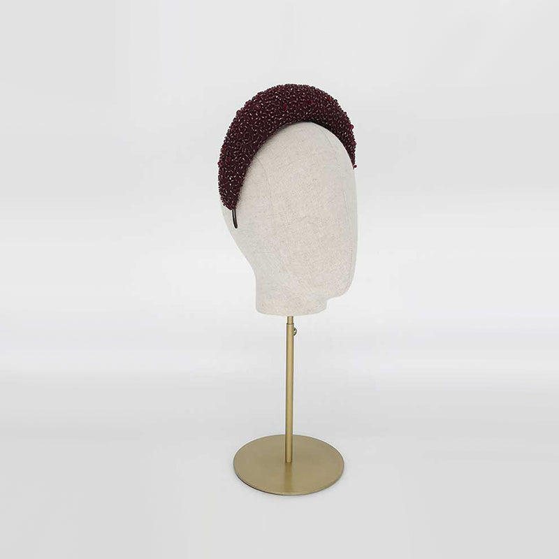Side view of a deep red silk beaded headband on a linen display head