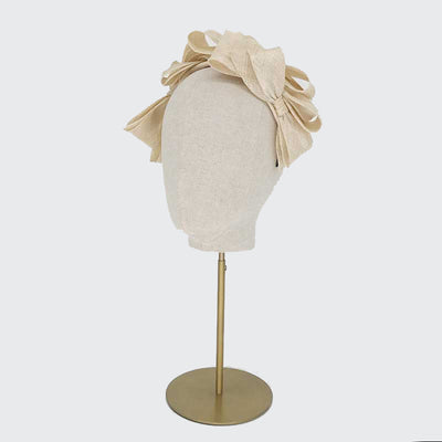 Side view of a natural fine straw bow headband on a linen display head