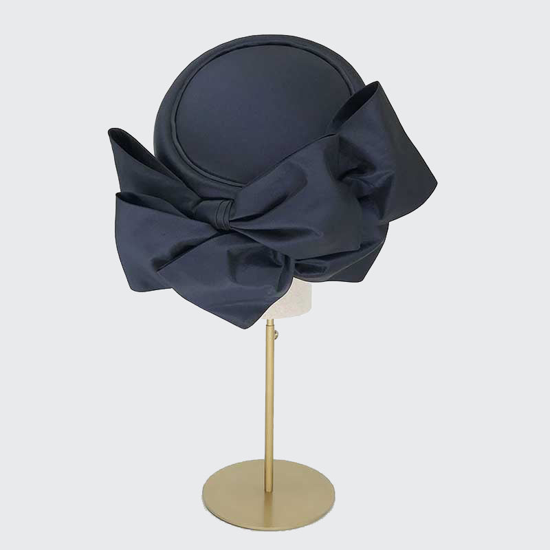 Back view of a navy taffeta silk Jackie O pillbox with bows on a linen display head