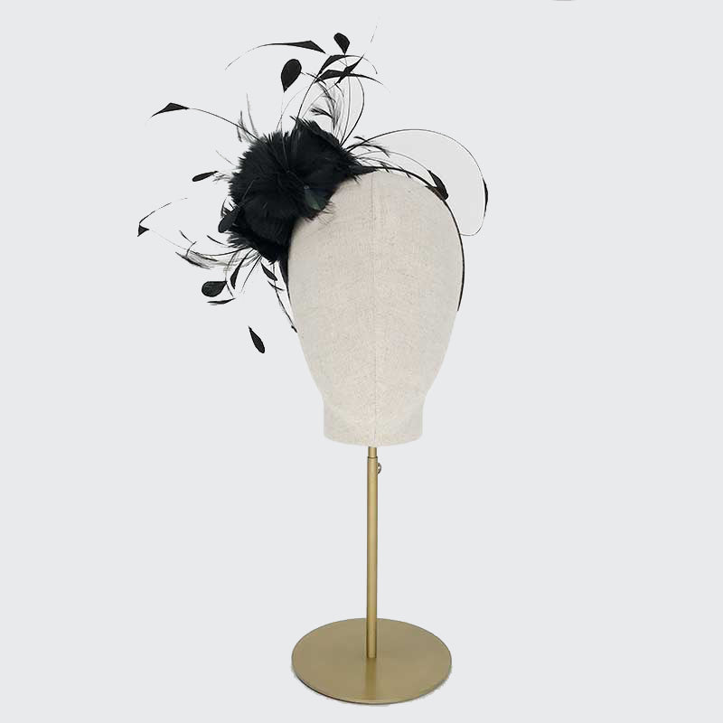 Photo of a black feather flower headband on a linen display head