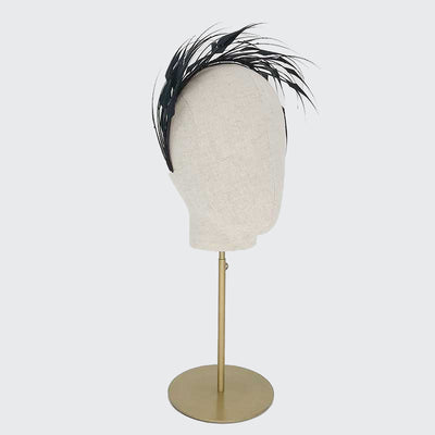 Side view of a black diamond-cut feather headband on a linen display head
