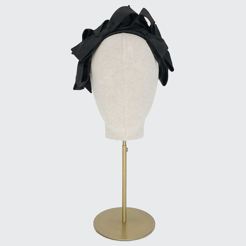 Photo of a black silk bow headband on a linen display head