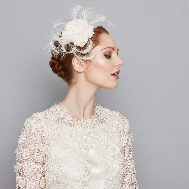 Bride wearing an ivory silk flower headband with curled feathers