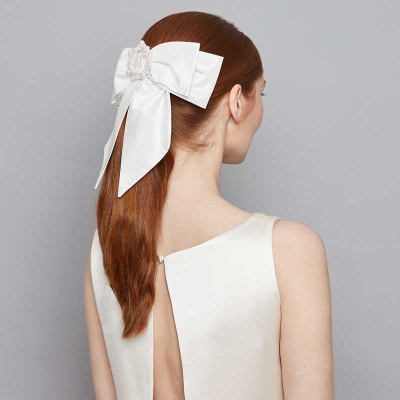 Bride wearing a large silk bow comb with pearl beading on a ponytail