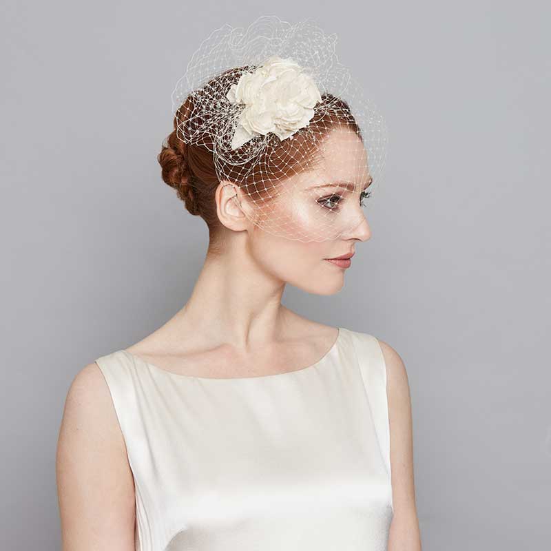 Bride wearing a silk flower crescent headband with birdcage