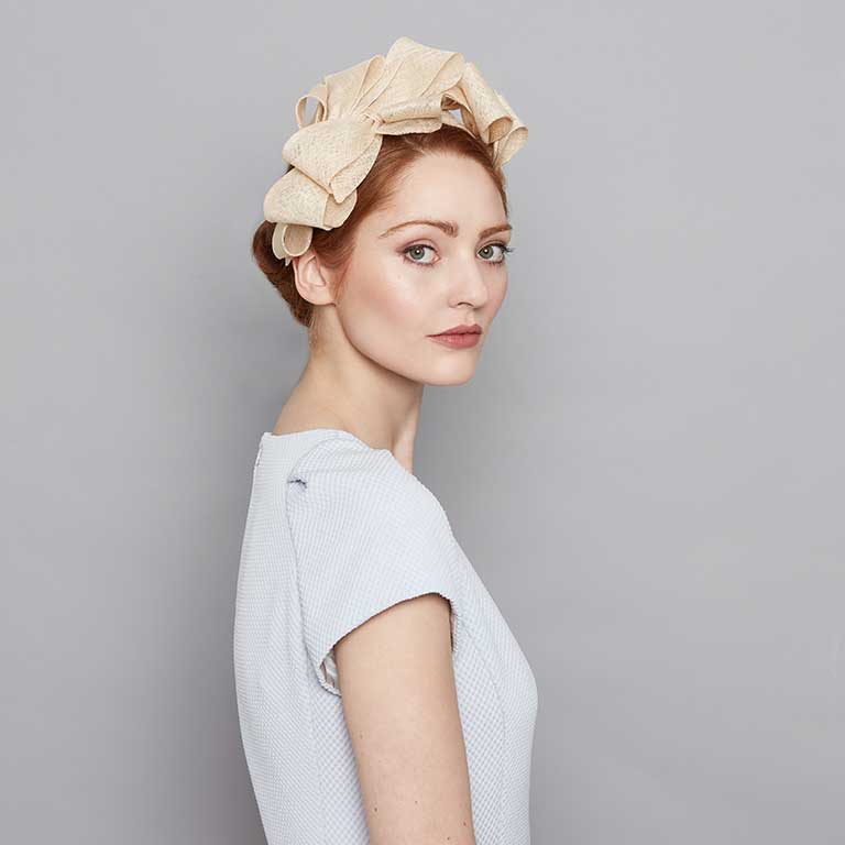 Woman with red hair wearing a pale blue dress and a natural fine straw bow headband