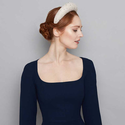Woman with red hair wearing a navy dress and a silver grey silk beaded raised headband