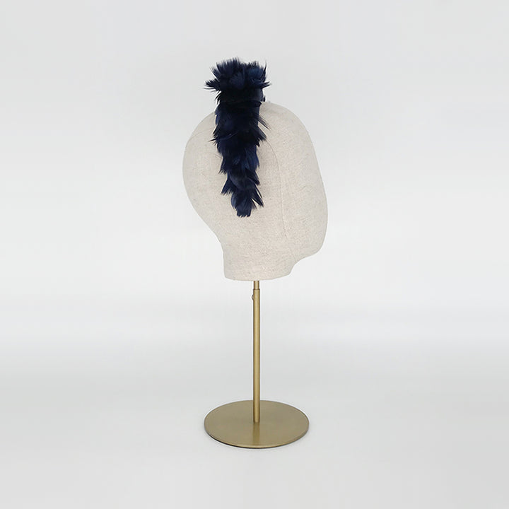 Side view of a navy goose feather headband on a linen display head