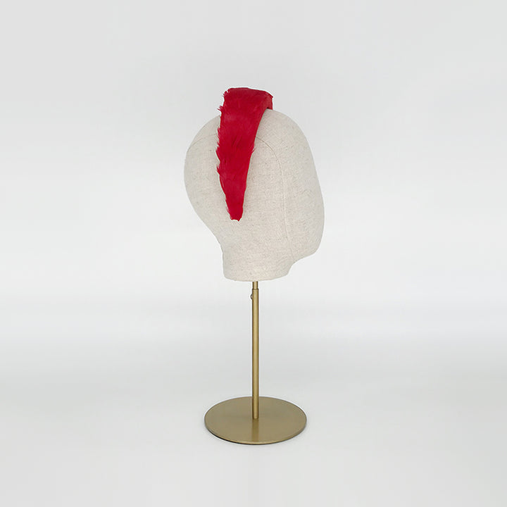Side view of a red goose feather headband on a linen display head