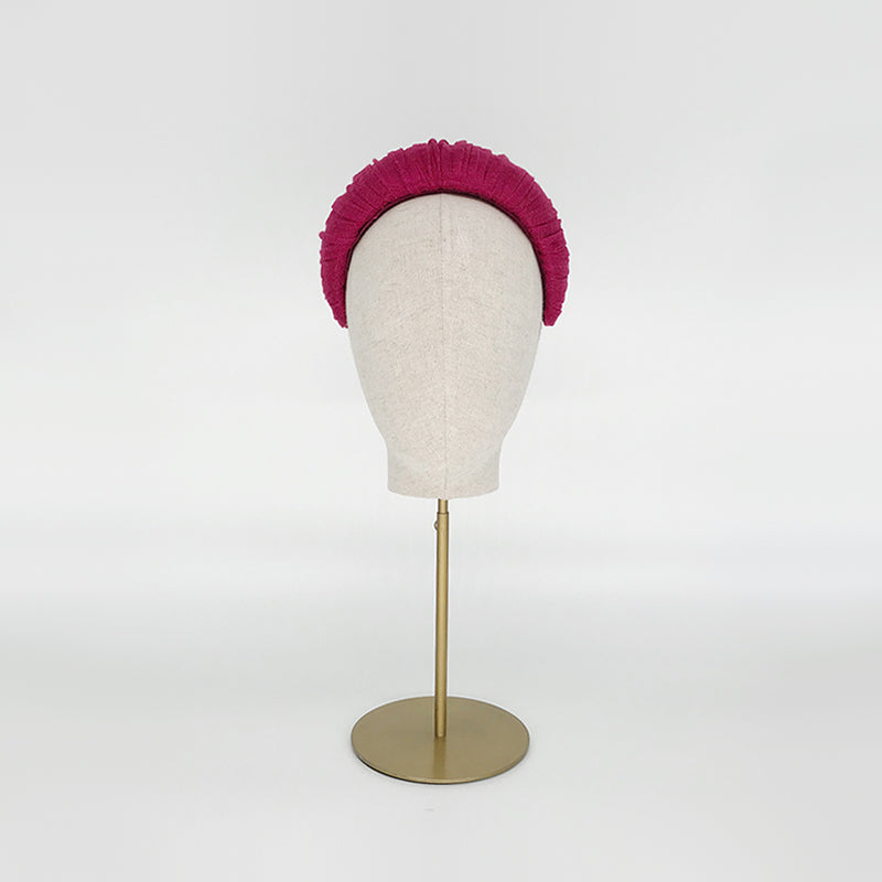 Photo of a pink pleated silk straw crescent on a linen display head