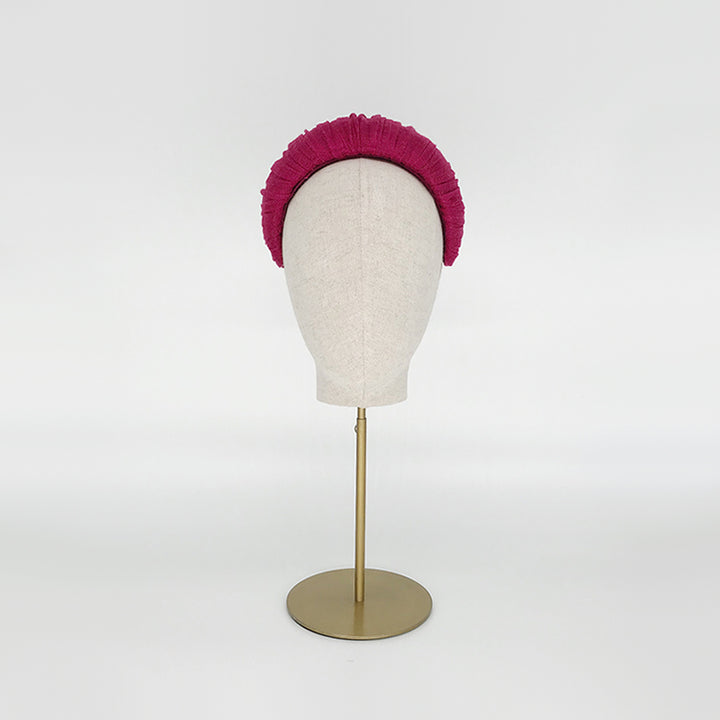 Photo of a pink pleated silk straw crescent on a linen display head