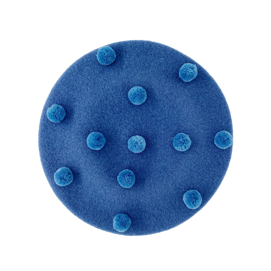 Photo of a denim blue wool beret with denim blue pom poms 