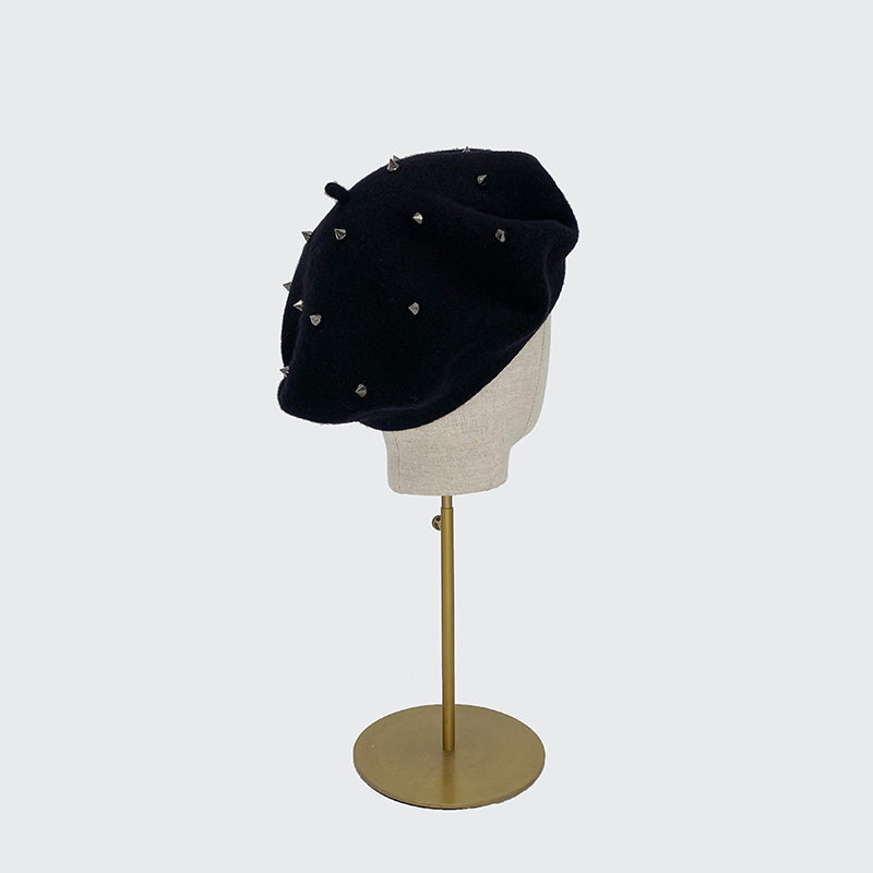 Photo of black wool beret with studs on a linen display head