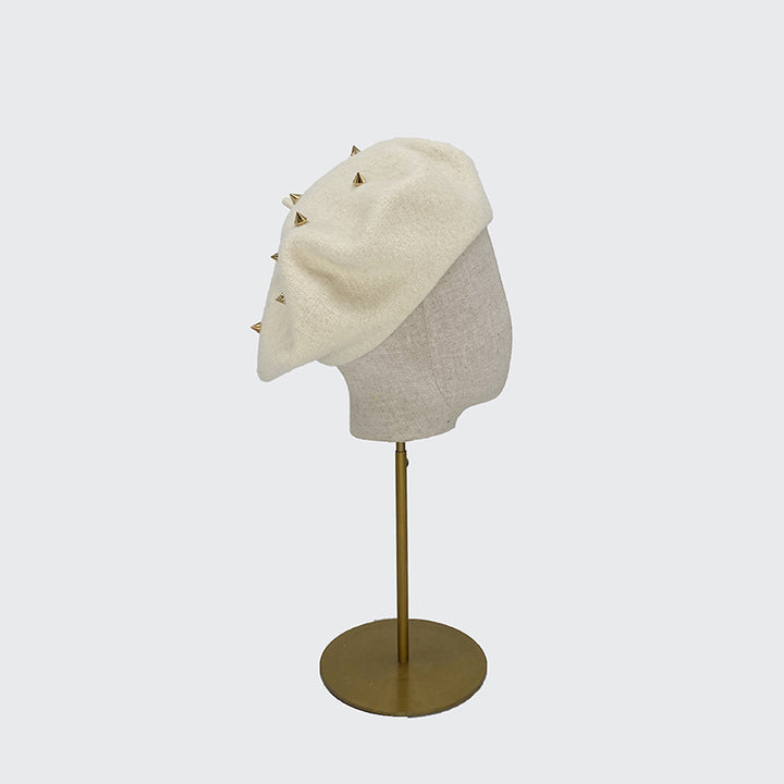 Side view of a white wool beret with gold studs