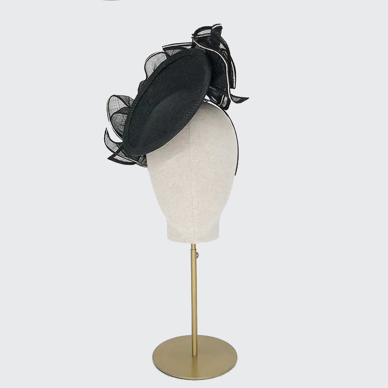 Photo of a black fine straw disc with a ruffle on a linen display head