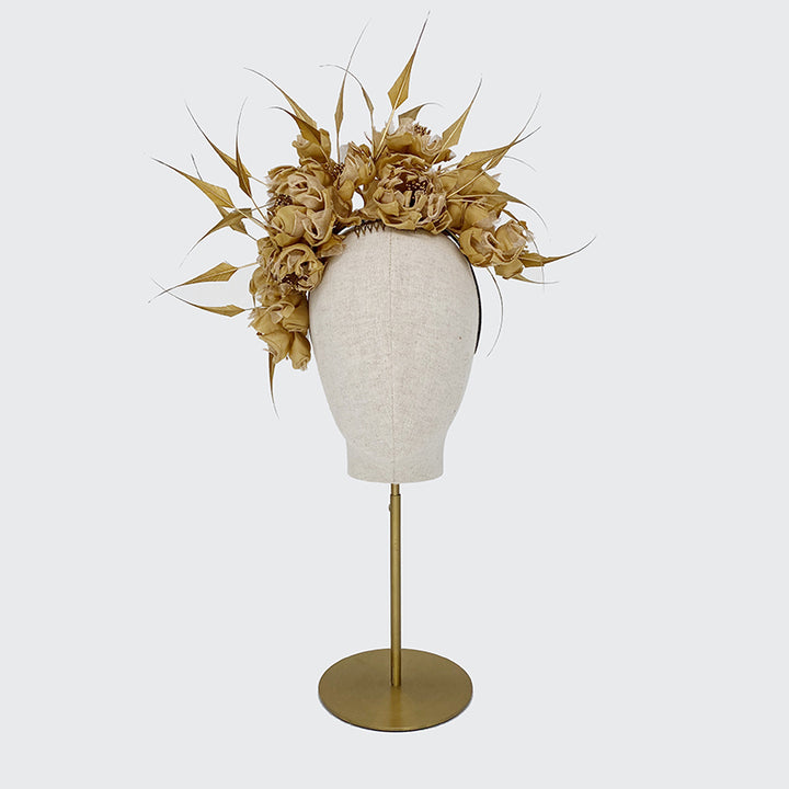 Photo of a brass gold silk headdress with diamond-cut feathers on a linen display head