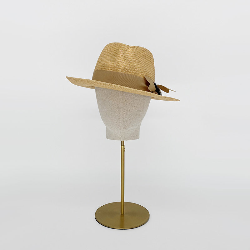 Photo of a natural panama trilby with a grosgrain bow on a linen display head